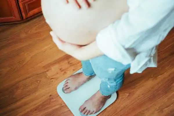 Image of woman weighing herself and experiencing weight gain through pregnancy Preston